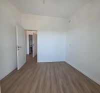 Interior of a 2-room apartment with wood-patterned flooring and white walls.