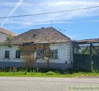 The old facade of a rural family house in Ozdín, surrounded by greenery and a fence.