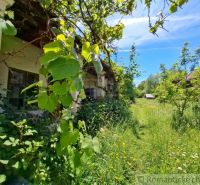 A family house in Ozdín with lush vegetation and older buildings in the background.