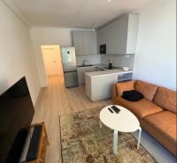 Living room with a sofa, TV, carpet, and kitchen in a 3-room apartment.