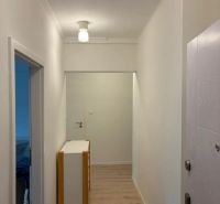 A hallway in a 3-room apartment with a wooden decor floor and white walls.