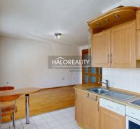 A kitchen in a three-room apartment with a wooden decor floor and light furniture.