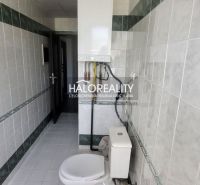 A bathroom with white tiles and a toilet in a 3-room apartment.