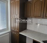A kitchen with a window, brown cabinets, and a white countertop in a three-room apartment.