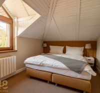 A bedroom in a 3-room apartment with a view of the mountains and a wooden ceiling.