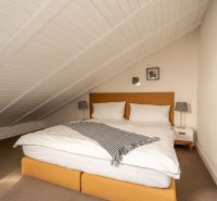 Attic bedroom in a 3-room apartment with a double bed and decorative lamps.