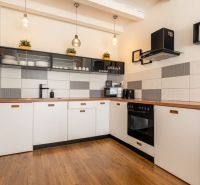 A kitchen in a 3-room apartment with a wooden decor floor and pendant lights.