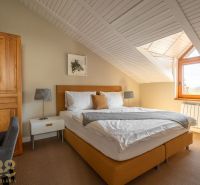 Attic bedroom with a double bed in a 3-room apartment, wooden ceiling, carpet.