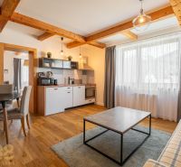 Living room with kitchen, wooden decor flooring, dining area and sofa.
