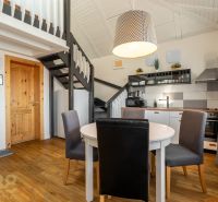 Interior of a 3-room apartment with a kitchen, dining table, and wood-patterned flooring.