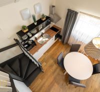 Interior of a 3-room apartment with a wooden decor floor, kitchen unit, and staircase.