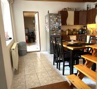 A kitchen in a family house with a dining table and magnets on the refrigerator.