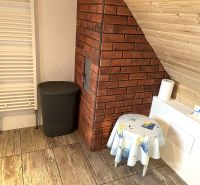 A bathroom in a family house with a wooden decor floor, red bricks, and a ladder radiator.