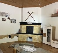 Interior of a family house with a tiled stove, wooden ceiling, and floor with a wooden decor.