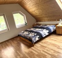 Bedroom in a family house with a bed and wooden decor flooring.