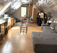 Attic room with a swing, seating, and a wooden decor floor in a family house.