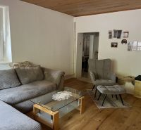 Living room with a comfortable sofa, armchair, and wooden decor flooring in a family house.