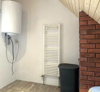 Boiler, radiator, and brick wall with wood-decorated flooring in a family house.