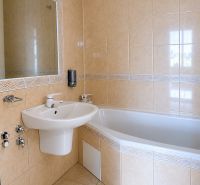 A bathroom with a corner bathtub and a sink in a 3-room apartment.