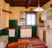 A kitchen in a cottage with traditional furnishings, a fabric curtain, and a floor with a wooden decor.