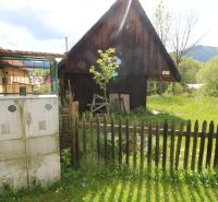 A wooden house in Žaškov on Matúšovská Street, surrounded by greenery and a fence. Construction of houses.