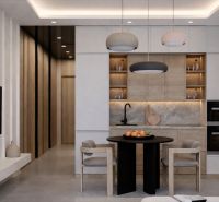 A kitchen in a studio apartment with wooden decor, modern lighting, and a dining table.