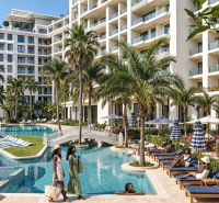 Elegant resort with a pool, palm trees, and relaxing guests.