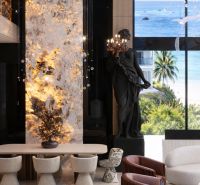 A dining room in a 5 or more bedroom apartment with a view of the beach, featuring a statue and decoration.
