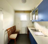 A kitchen space with blue cabinets and white tiles, three wooden chairs.