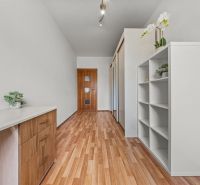 A hallway with a wooden decor floor and white furniture in a 4-room apartment.