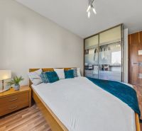 Bedroom in a 4-room apartment with wood-patterned flooring, a wardrobe, and a crib.