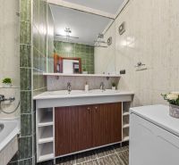 A bathroom with green tiles, a double sink, and a washing machine in a 4-room apartment.