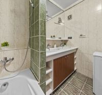A bathroom with a shower, sink, and washing machine in a 4-room apartment.