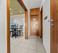 A hallway with a light floor and wooden doors leading to the dining room in a 4-room apartment.