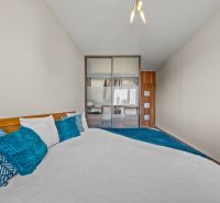 A bedroom in a 4-room apartment with decorative pillows and a built-in wardrobe.