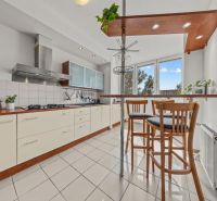 A kitchen in a 4-room apartment with seating at the bar counter and appliances.