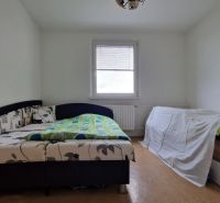 A bedroom with a light floor and two beds in a two-room apartment.