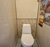 Compact toilet in a 2-room apartment with patterned walls and tiles.