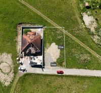 Lietavská Svinná-Babkov: A plot for living, a green meadow with a house under construction and vehicles.
