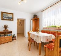 Dining area in a family house with wooden seating, a painting, and floral decorations.