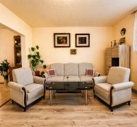 Living room with a sofa, armchairs, a glass table, and a wooden decor floor.