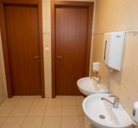 Office restroom with two sinks and a door, tiled with ceramic tiles.