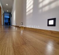 A hallway in a family house with a wooden decor floor and integrated lighting.