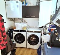 Laundry room in a family house with a washing machine, dryer, and storage space. Floor with wood decor.