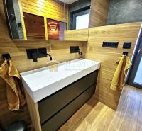 A bathroom in a family house with a wooden decor floor and equipment with a mirror.