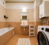 A bathroom in a 2-room apartment with a bathtub, washing machine, and gas boiler.