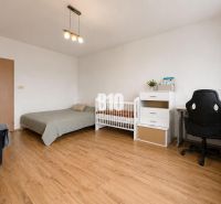 Children's room in a two-room apartment with a bed, a desk, and a wooden decor floor.