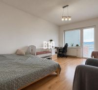 A bright room with a bed, a crib, and a wooden decor floor in a 2-room apartment.