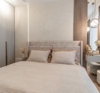 A bedroom in a 3-room apartment with a bed, wardrobe, and elegant lighting.