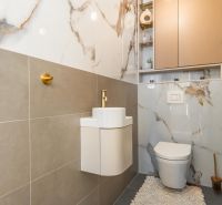 A bathroom in a 3-room apartment with a combination of ceramic tiles and gold accessories.